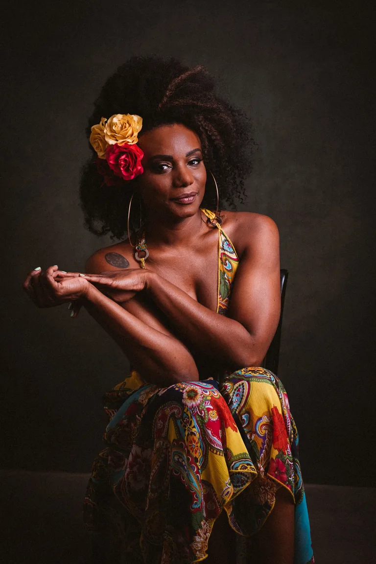 Editorial studio portrait, red and yellow flowers in natural hair, bright patterned wrap